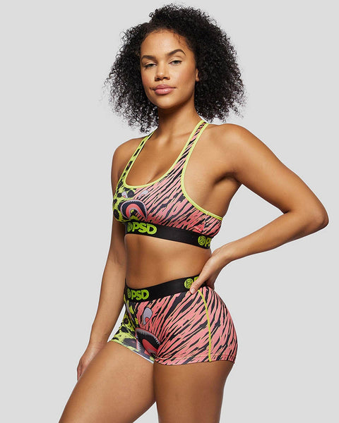 Woman wearing red and neon yellow tiger-stripe sports bra and shorts set with black waistbands.