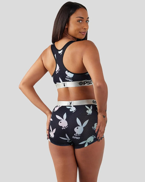 Woman wearing black sports bra and shorts with white Playboy bunny pattern and silver PSD waistband, shown from back.