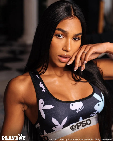 Woman wearing black Playboy sports bra with white bunny logo pattern and PSD waistband.