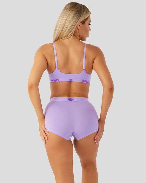 Woman wearing lavender bra and matching high-waisted briefs with branded waistband, shown from back view.