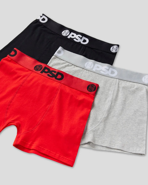 Three PSD brand boxer briefs in black, red, and gray with elastic waistbands displayed stacked together.