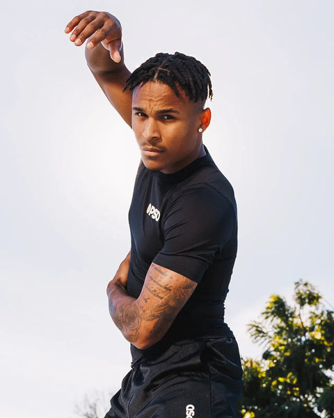 Black short-sleeve compression tee with small white logo on chest, fitted silhouette.