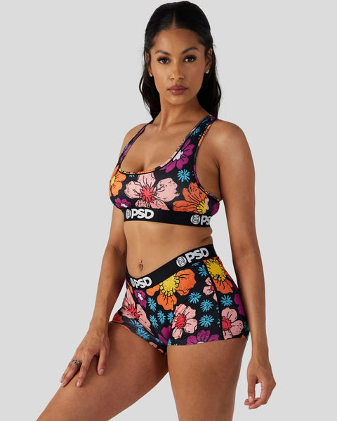 Woman wearing colorful floral print sports bra and matching shorts with black PSD waistbands.
