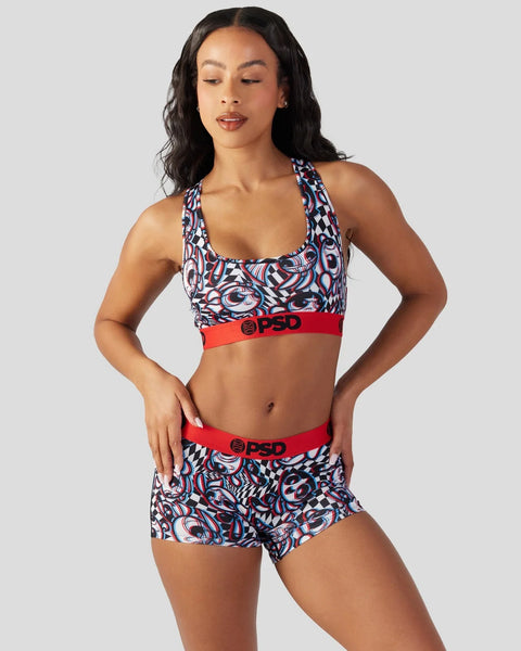Woman wearing a multi-colored geometric patterned sports bra and matching shorts with red waistbands.