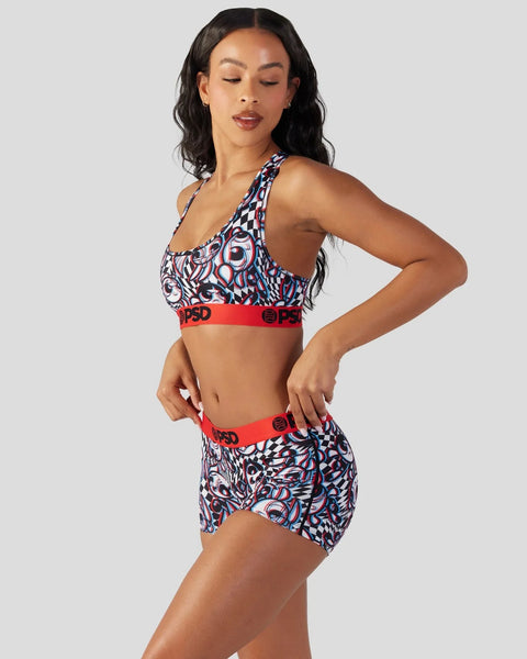 Woman wearing a two-piece swimsuit with abstract blue, red, and white patterned top and matching shorts with red elastic band