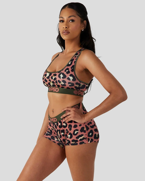 Woman wearing coral and black leopard print sports bra and shorts set with olive green trim.