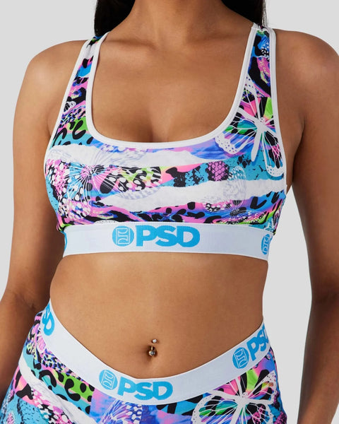 White sports bra with neon pink, blue, green, and black animal and floral pattern, PSD branding on elastic band.