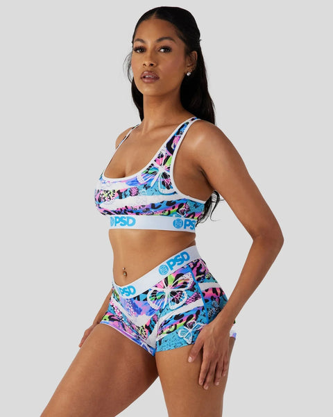 Woman wearing neon tropical print sports bra and matching shorts with blue waistband.
