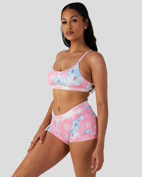Woman wearing pink and blue floral sports bra and matching shorts with contrasting trim.