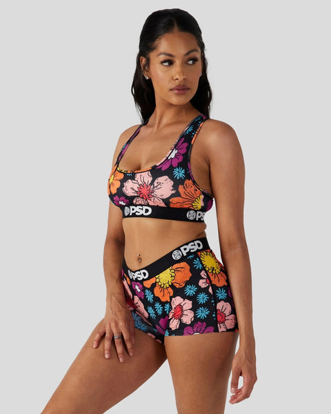 Woman wearing multicolored floral print sports bra and shorts set with black PSD waistbands.