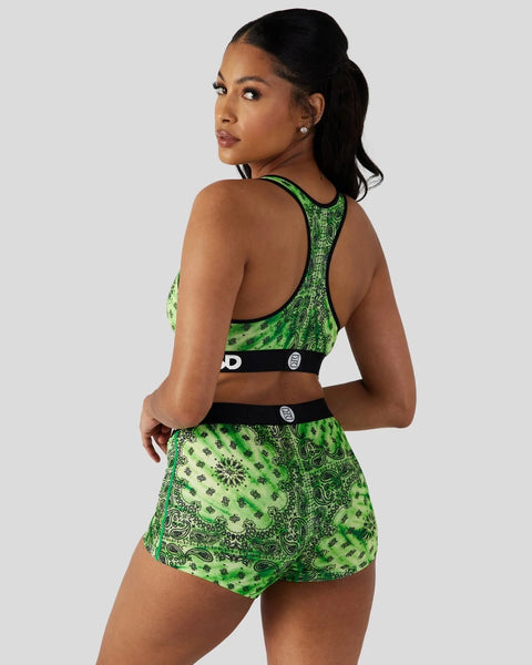 Woman wearing green and black patterned sports bra and matching shorts with black waistband trim.