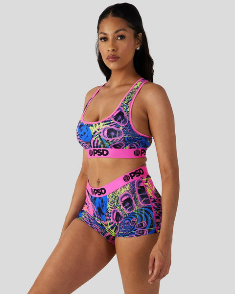 Woman wearing colorful neon grid-patterned sports bra and matching shorts with pink trim and PSD branding.