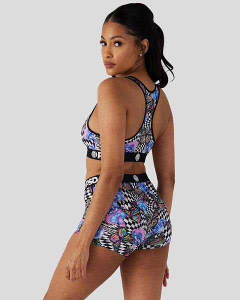 Woman wearing a black and multicolored floral patterned sports bra and matching shorts with houndstooth details, shown from t