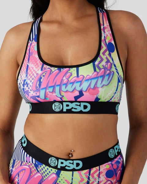 Colorful neon sports bra with "Miami" text, geometric patterns, and PSD waistband in pink, purple, blue, and yellow.