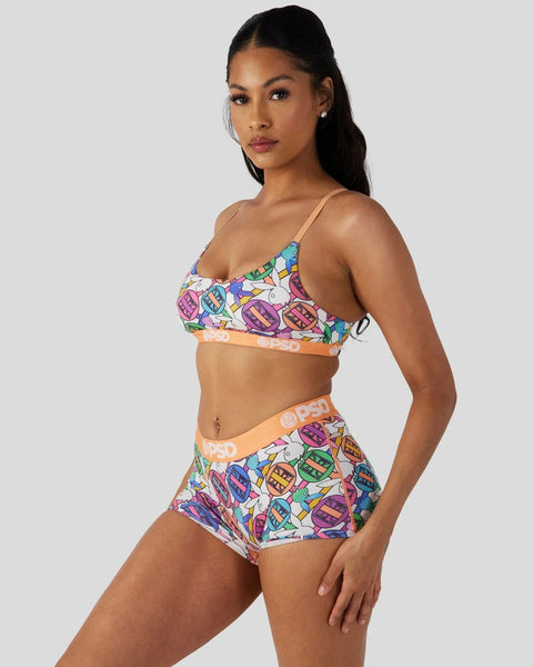 Woman wearing Playboy Geo two-piece swimsuit with colorful geometric lip print pattern and orange waistband detail.