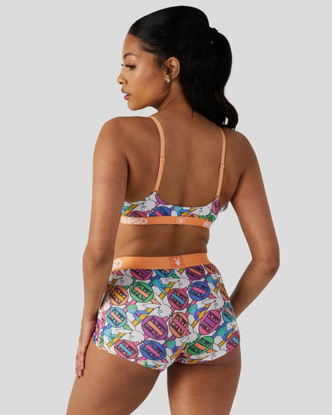 Woman wearing a multicolored geometric patterned bra and shorts set with orange elastic bands, shown from behind.