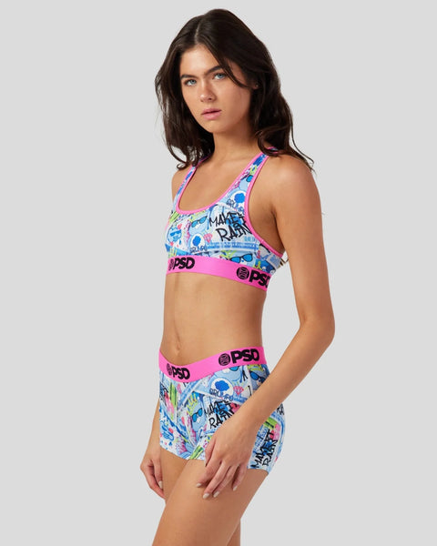 Woman wearing multicolor Care Bears print sports bra and shorts set with pink waistband and branding.