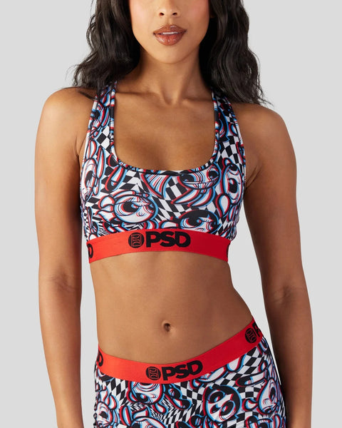 Woman wearing a red and blue abstract patterned sports bra with red waistband featuring PSD branding.
