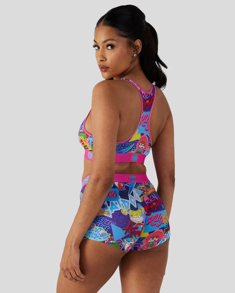 Woman wearing colorful racerback sports bra and matching shorts with cartoon character print and geometric patterns.