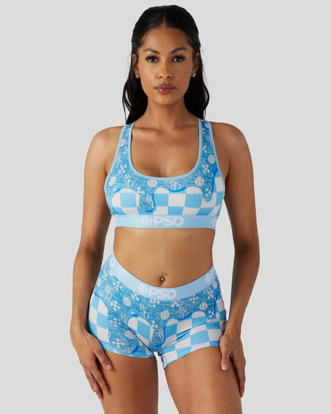 Woman wearing blue and white patterned sports bra and matching shorts with geometric denim-print design.