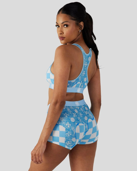 Woman wearing a blue and white patterned sports bra and matching shorts set with geometric designs.