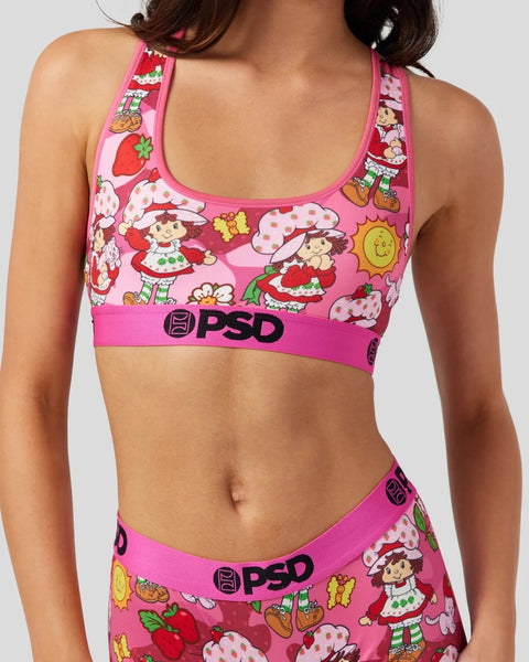 Pink sports bra with Strawberry Shortcake characters, strawberries, and PSD branding on elastic band.