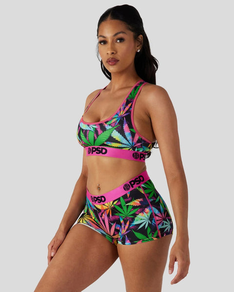 Woman wearing colorful neon leaf-print sports bra and matching shorts with pink PSD branding.