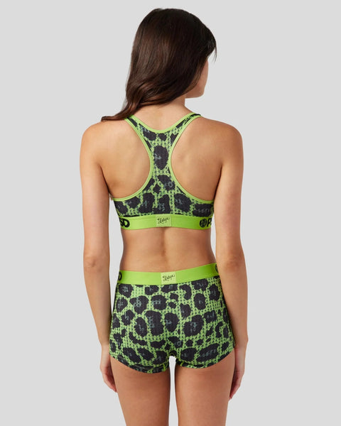 Woman wearing neon green and black cheetah print sports bra and shorts set with rhinestone details, shown from back.