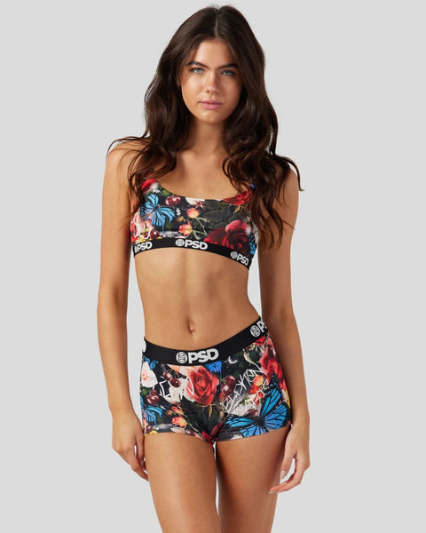 Woman wearing black sports bra and shorts with red roses and blue butterflies print and PSD waistbands.