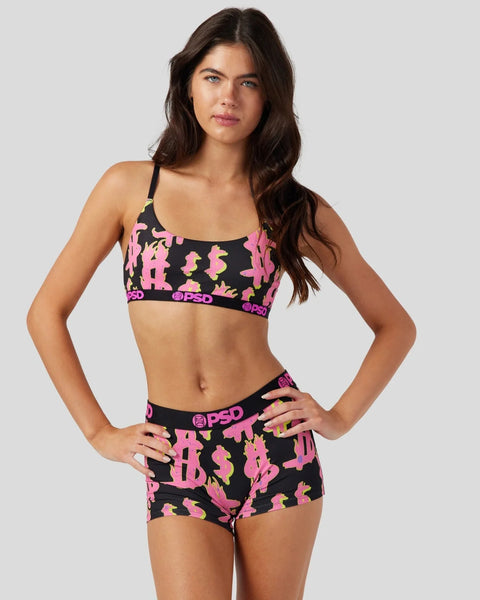 Woman wearing black sports bra and shorts with pink and yellow dollar sign pattern and PSD waistband.
