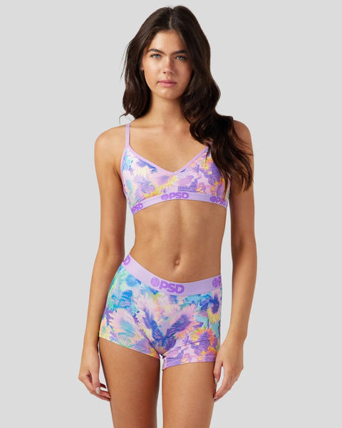 Woman wearing purple floral bra and matching shorts with colorful butterfly and flower print.