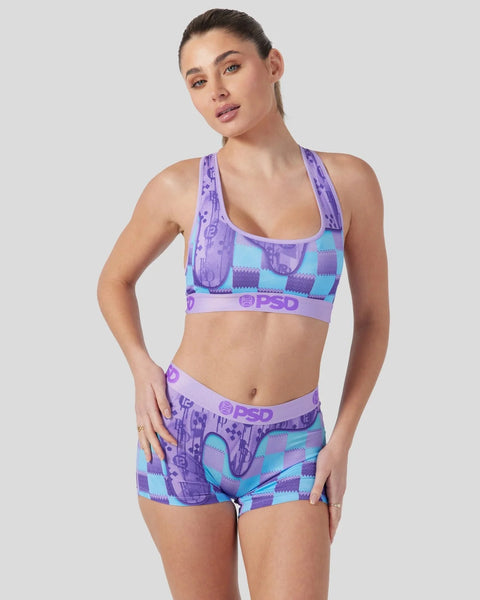 Woman wearing purple and teal patterned sports bra and matching shorts with PSD branding.