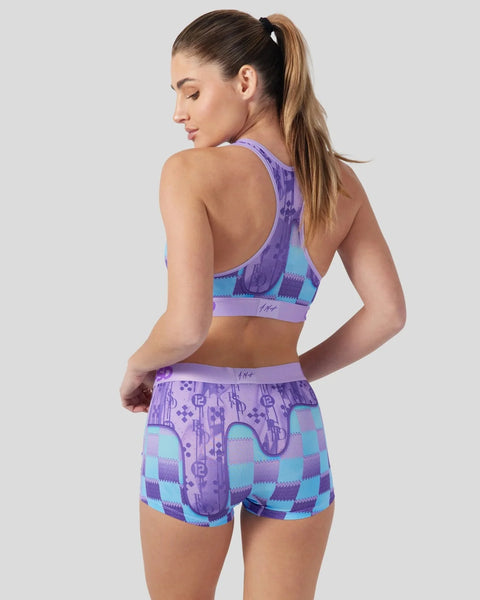Woman wearing purple and turquoise patterned sports bra and shorts set with geometric design.