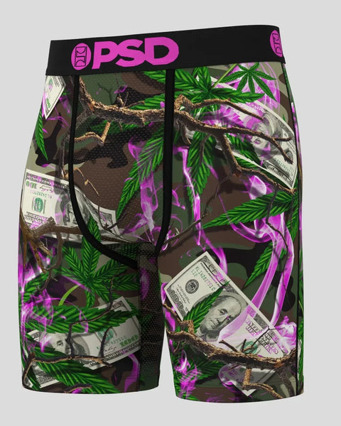 PSD brand shorts with camouflage pattern featuring green leaves, brown branches, purple neon accents, and dollar bill graphic