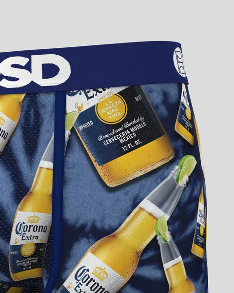 Corona Extra beer bottles with lime wedges on blue fabric packaging with white branding text.