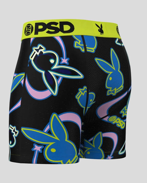 Black boxer shorts with neon blue and yellow Playboy bunny heads, stars, and geometric shapes; lime green PSD waistband.