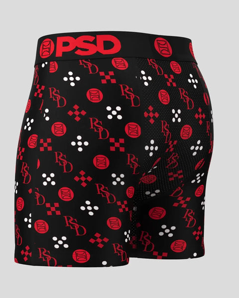 Black boxer shorts with red and white repeating geometric and logo pattern, black waistband with red PSD branding.