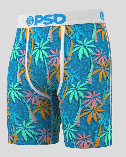 PSD brand boxer shorts with blue background and multicolored tropical leaf and palm tree pattern.