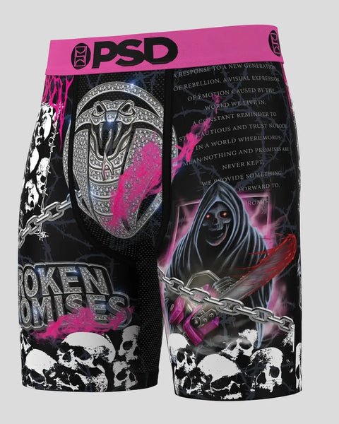 Black shorts with pink PSD waistband, featuring decorative skull, chainsaw, and ornamental designs throughout.