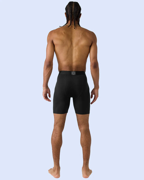 Man wearing black modal shorts with elasticated waistband, shown from behind against light blue background.