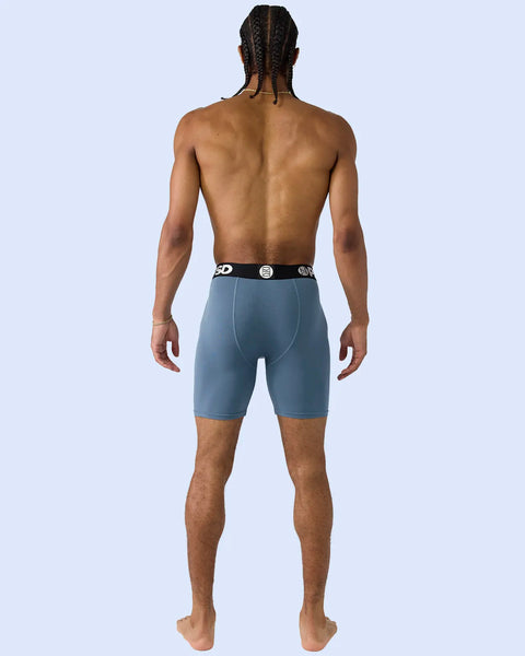 Man wearing teal modal boxer briefs with black waistband, rear view.