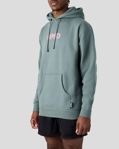Man wearing dusty sage pullover hoodie with pink PSD logo on chest and front kangaroo pocket.