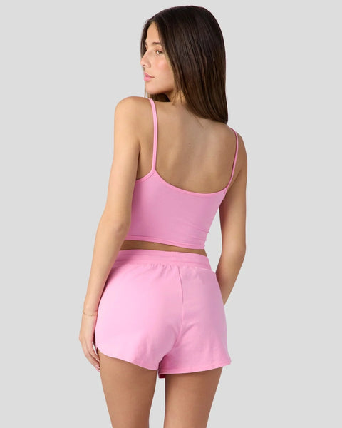 Woman wearing bubblegum pink cami top and matching shorts sleep set, shown from back.