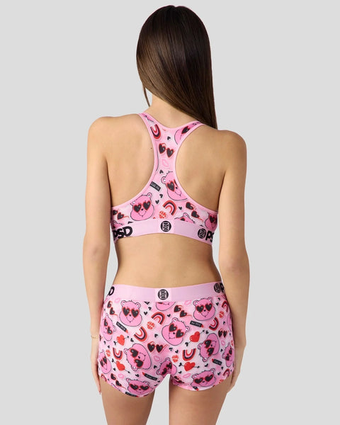 Pink two-piece set with Love Bear character print, hearts, and curved design elements on racerback top and shorts.