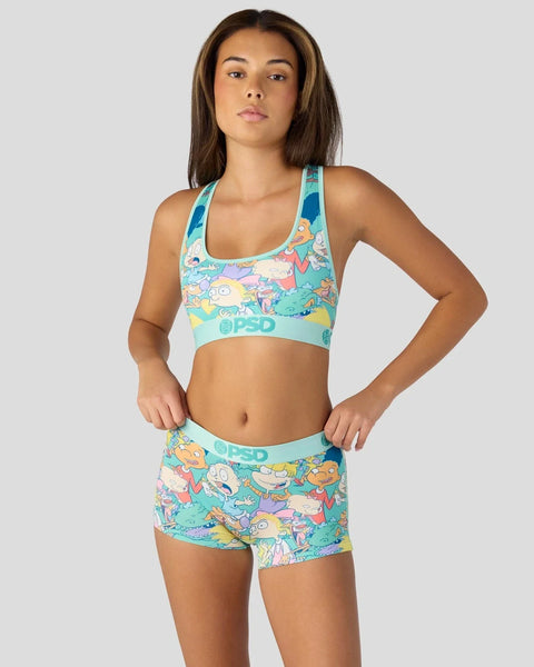 Woman wearing turquoise sports bra and shorts with colorful Nickelodeon cartoon character print and PSD branding.