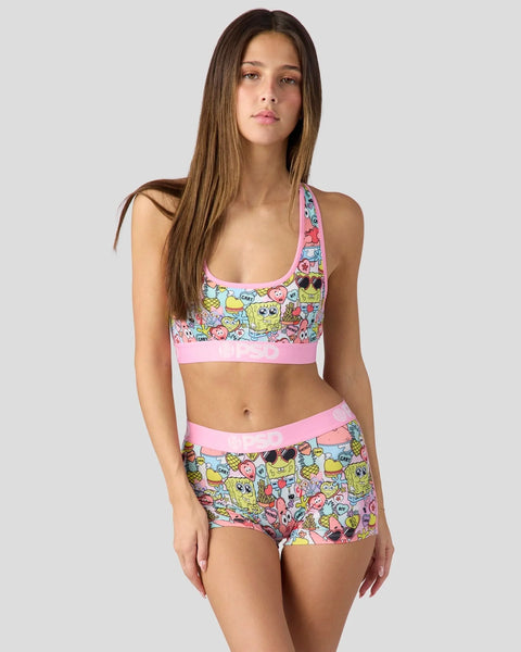 Woman wearing SpongeBob SquarePants printed sports bra and shorts set with pink trim and colorful cartoon characters.