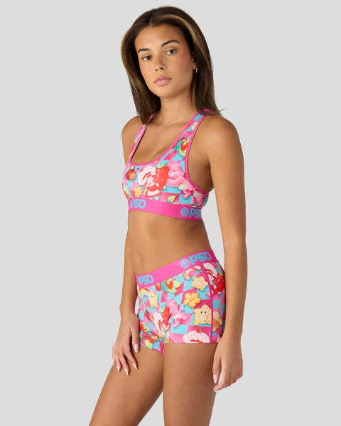 Woman wearing bright pink sports bra and shorts with colorful cartoon character print and matching waistband design.