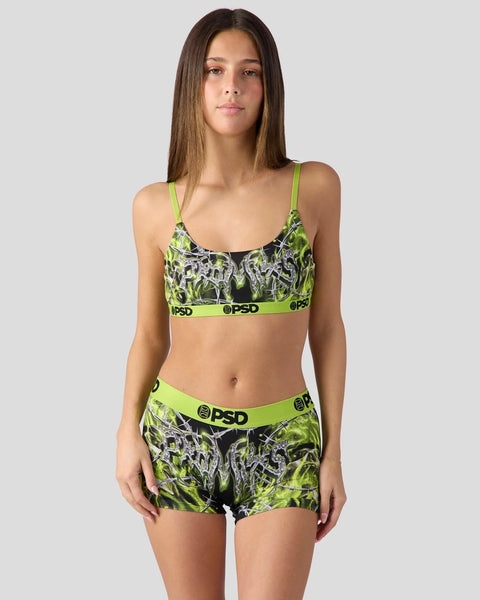 Woman wearing neon yellow and black patterned sports bra and shorts set with PSD branding.