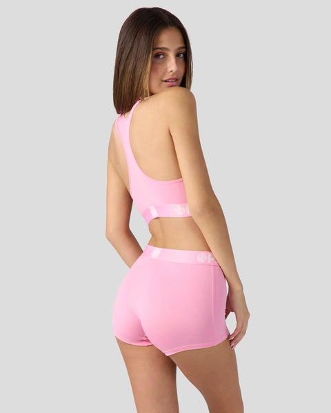 Woman wearing pink sleeveless crop top and matching shorts with elastic waistbands.
