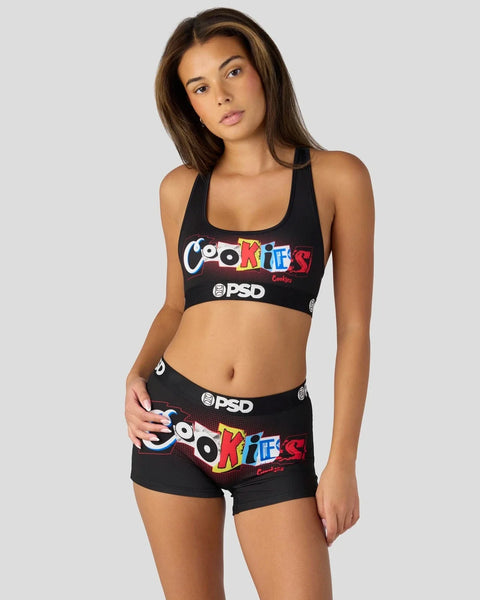 Woman wearing black sports bra and shorts set with colorful "Cookies" branding and PSD logo on front.
